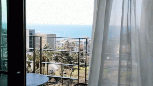 A Balcony With A View Of The Ocean And A Table GIF