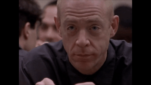 A Bald Man In A Black Shirt Is Making A Face GIF