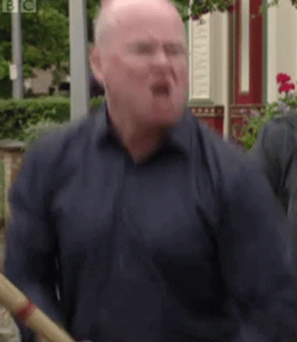 A Bald Man In A Blue Shirt Is Holding A Bamboo Stick . GIF