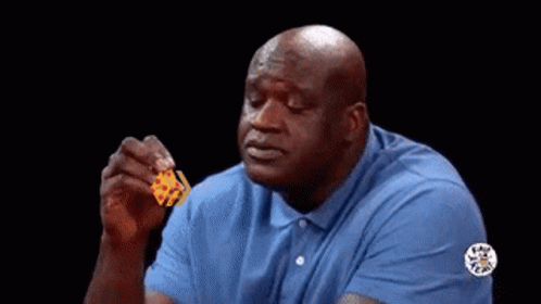 A Bald Man In A Blue Shirt Is Holding A Piece Of Cheese In His Hand . GIF