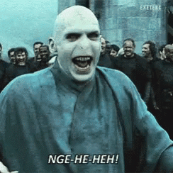 A Bald Man In A Blue Shirt Says Nge-He-Heh In Front Of A Crowd GIF