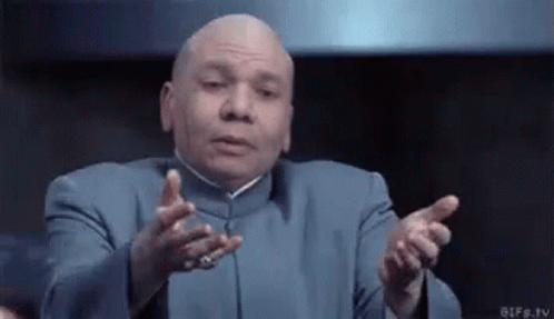 A Bald Man In A Blue Suit Is Making A Funny Face With His Hands Outstretched GIF