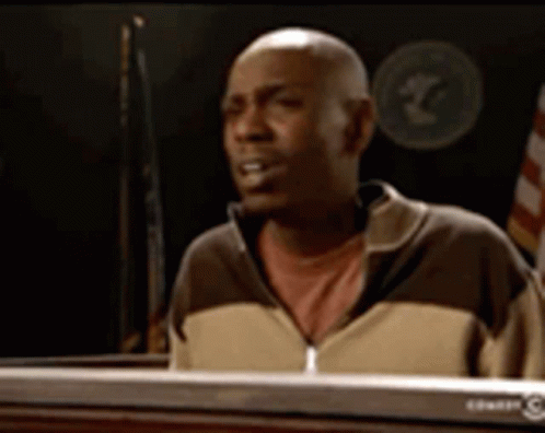 A Bald Man In A Brown And Tan Jacket Is Sitting At A Keyboard GIF