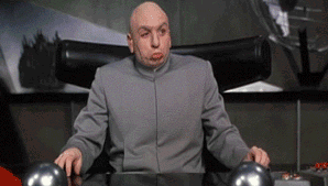 a bald man in a gray suit is sitting at a desk making a funny face