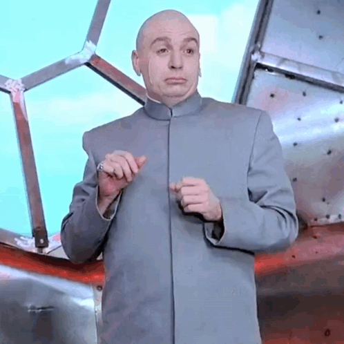 A Bald Man In A Gray Suit Is Standing In Front Of A Window . GIF