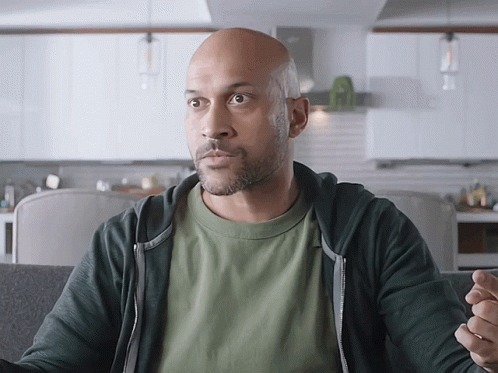 A Bald Man In A Green Shirt And Black Hoodie GIF
