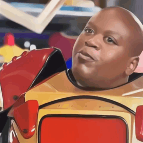 A Bald Man In A Red And Yellow Robot Costume Looks At The Camera GIF