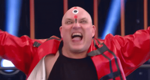 a bald man in a red jacket has a circle on his forehead