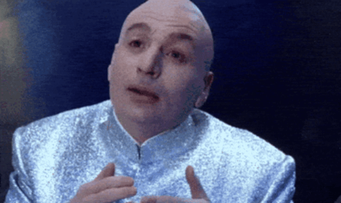 A Bald Man In A Silver Suit Is Talking GIF
