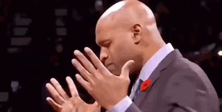 A Bald Man In A Suit And Tie Is Clapping His Hands Together . GIF