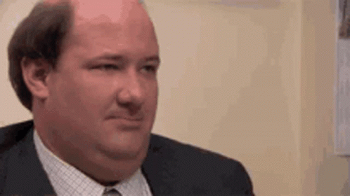 A Bald Man In A Suit And Tie Is Making A Face . GIF