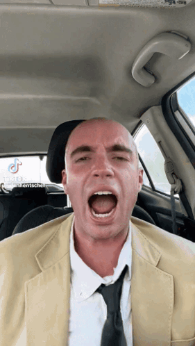 A Bald Man In A Suit And Tie Is Screaming In The Back Seat Of A Car GIF