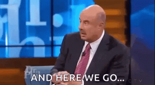 A Bald Man In A Suit And Tie Is Sitting On A Stage Talking On A Talk Show . GIF