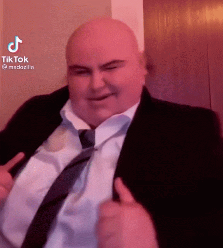 A Bald Man In A Suit And Tie Is Smiling And Giving A Thumbs Up GIF