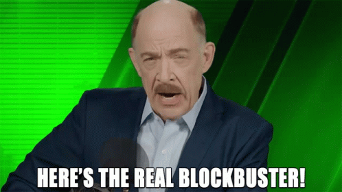 A Bald Man In A Suit And White Shirt Says Here 'S The Real Blockbuster In Front Of A Green Background GIF