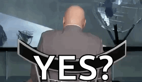 A Bald Man In A Suit Is Sitting In Front Of A Sign That Says Yes ? GIF