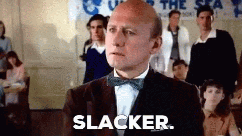 A Bald Man In A Tuxedo And Bow Tie Is Standing In Front Of A Group Of People . GIF