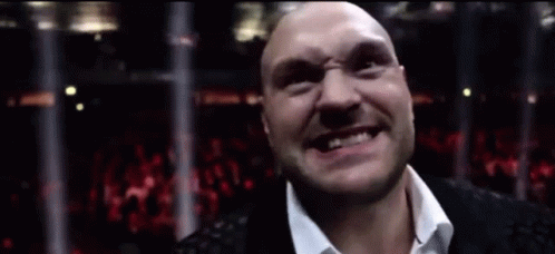 A Bald Man In A White Shirt Is Smiling In Front Of A Crowd GIF