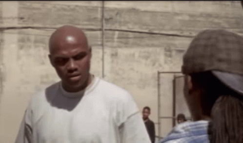 a bald man in a white shirt is talking to a woman in a hat .
