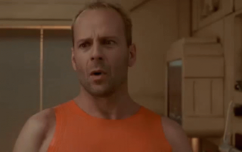 A Bald Man In An Orange Tank Top Is Standing In Front Of A Sign That Says I Am Not Going GIF
