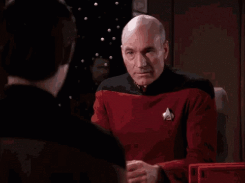 A Bald Man Is Covering His Face With His Hands While Another Man Looks On GIF