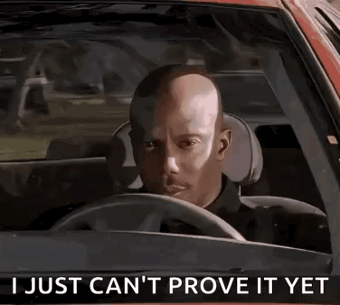 A Bald Man Is Driving A Car With The Words `` I Just Can 'T Prove It Yet '' Written On The Steering Wheel . GIF