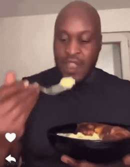 A Bald Man Is Eating Food With A Spoon From A Bowl . GIF