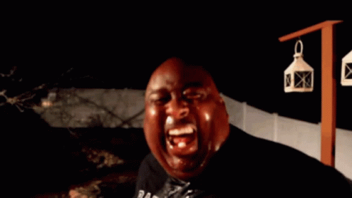 A Bald Man Is Holding A Bottle In His Hand And Looking At The Camera GIF