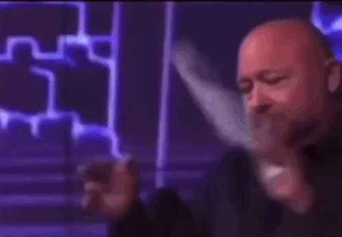 A Bald Man Is Holding A Cell Phone In His Hand And Says Liberal . GIF
