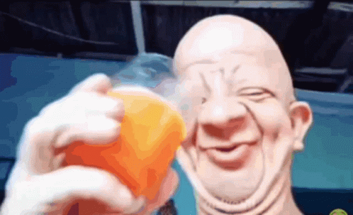 A Bald Man Is Holding A Cup Of Orange Juice And Smiling GIF