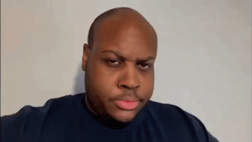 A Bald Man Is Making A Funny Face While Pointing At The Camera . GIF