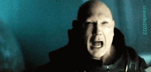 A Bald Man Is Screaming In A Dark Room With A Blue Background And A Watermark That Says Cavallo023 GIF