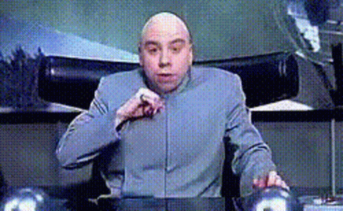 A Bald Man Is Sitting At A Desk With His Hand On His Chin GIF