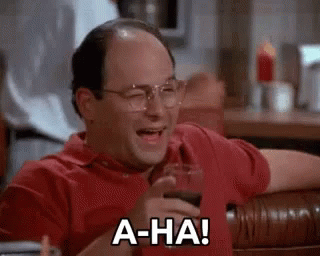 A Bald Man Is Sitting At A Table With A Glass Of Wine And Laughing . GIF