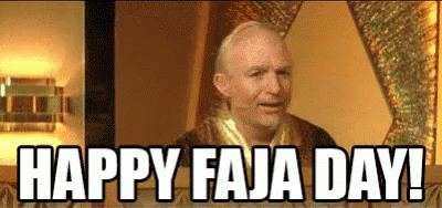 A Bald Man Is Sitting At A Table With The Words `` Happy Faja Day '' Written On The Screen . GIF