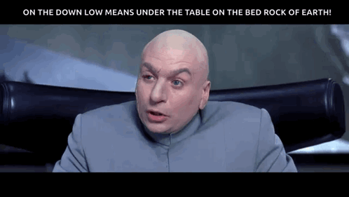 A Bald Man Is Sitting In A Chair With The Words On The Down Low Means Under The Table On The Bed Rock Of Earth Below Him GIF