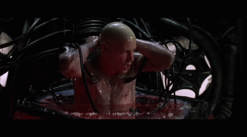 A Bald Man Is Sitting In A Red Liquid GIF