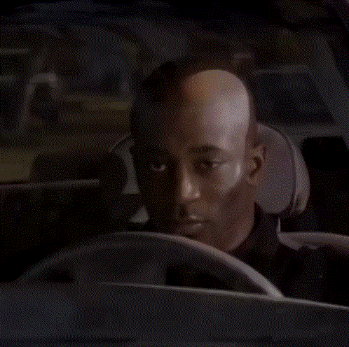 A Bald Man Is Sitting In The Driver 'S Seat Of A Car . GIF