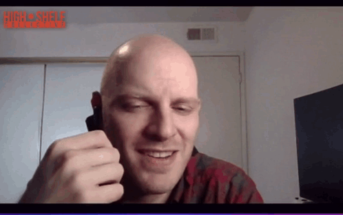 A Bald Man Is Smiling In Front Of A Screen That Says High Shelf Interactive GIF