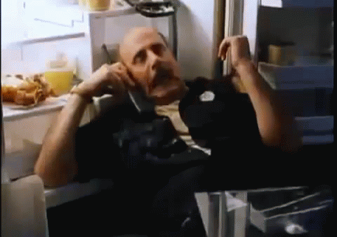 A Bald Man Is Talking On A Cell Phone In A Refrigerator . GIF