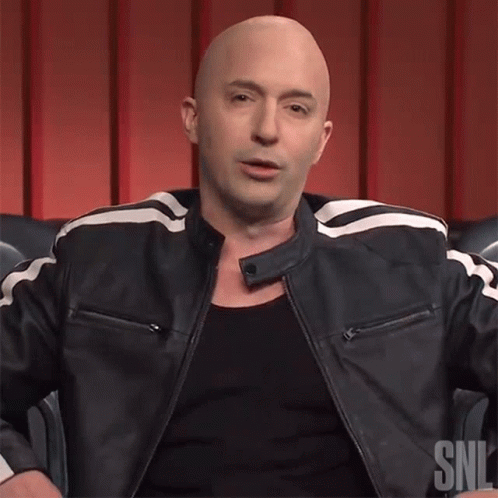 A Bald Man Is Wearing A Black Shirt And A Black Leather Jacket With A Snl Logo On It GIF
