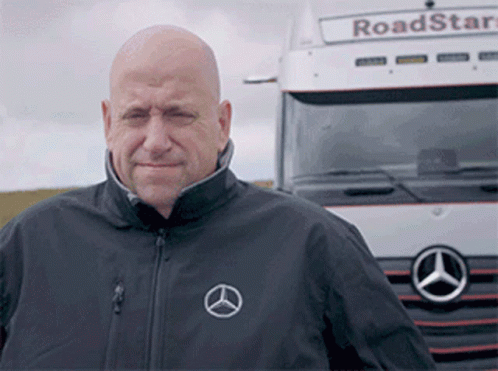 A Bald Man Stands In Front Of A Mercedes Truck GIF