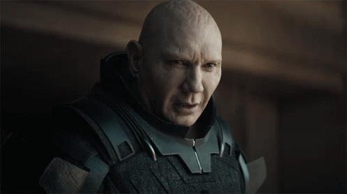A Bald Man Wearing A Black Armored Suit Looks At The Camera GIF