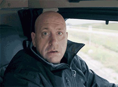 A Bald Man Wearing A Black Jacket Looks Surprised GIF