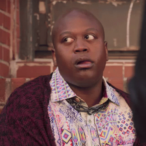 A Bald Man Wearing A Colorful Shirt And A Purple Cardigan Looks Surprised GIF
