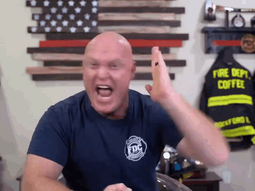 A Bald Man Wearing A Fire Dept Coffee Shirt Is Giving A High Five GIF