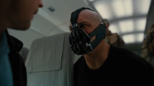 A Bald Man Wearing A Mask Talks To Another Man GIF