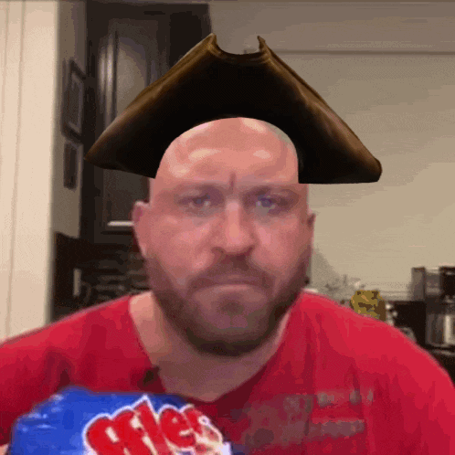 A Bald Man Wearing A Pirate Hat Holds A Bag Of Mrs. Potato Chips GIF