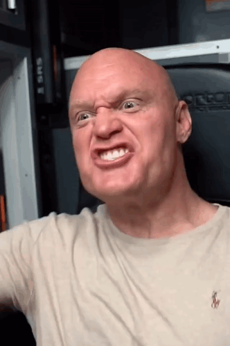 A Bald Man Wearing A Polo Shirt Is Making An Angry Face GIF