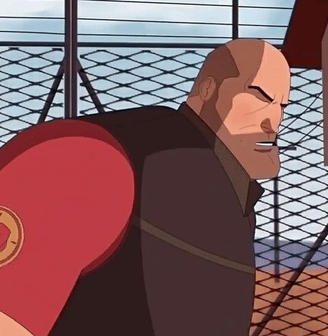 A Bald Man Wearing A Red Boxing Glove With A Circle On It Is Standing In Front Of A Chain Link Fence GIF